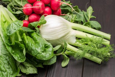 Taze yeşil marul, romaine ve rezene yaprakları. Bir avuç turp. Kapatın. Ahşap arkaplan