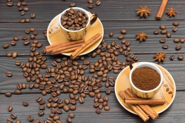 Kahve ve kavrulmuş kahve çekirdekleri. Tarçın tabağa yapışıyor. Kahve çekirdekleri ve yıldız anason masada. Karanlık ahşap arka plan. Düz yatıyordu