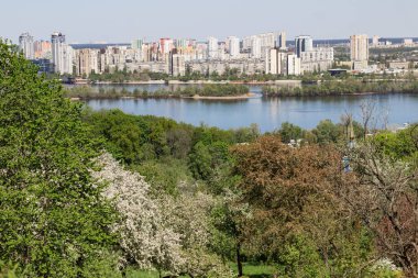 Şehir manzarası. Bahar Parkı. Nehir kıyısındaki yüksek binalar.