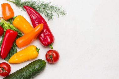 Farklı renkte biberler, salatalık ve domates. Beyaz arka plan. Düz yatıyordu. Boşluğu kopyala