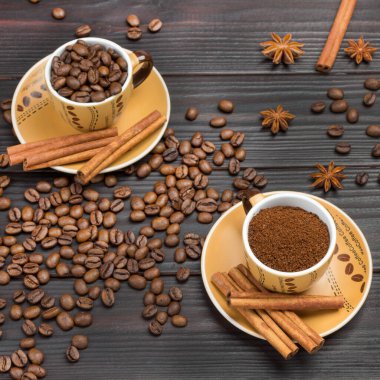Kahve ve kavrulmuş kahve çekirdekleri. Tarçın tabağa yapışıyor. Kahve çekirdekleri ve yıldız anason masada. Karanlık ahşap arka plan. Düz yatıyordu