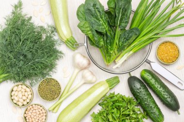 Taze ıspanak ve süzgeçte yeşil soğan yaprağı. Nohut, fasulye ve fındık. Sarımsak, salatalık ve kabak. Beyaz arka plan. Düz yatıyordu