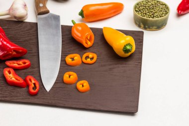 Kesme tahtasında dilimlenmiş biber ve bıçak. Yeşil kasede Mung fasulyesi. Beyaz arka plan. Üst görünüm