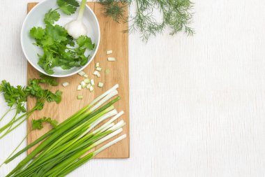 Beyaz kasede kilantro ve sarımsak. Kesme tahtasındaki taze soğanlar. Uzayı kopyala Beyaz arkaplan