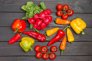 Masada çok renkli biber, turp ve domates sosu var. Koyu ahşap arka plan. Düz yatıyordu