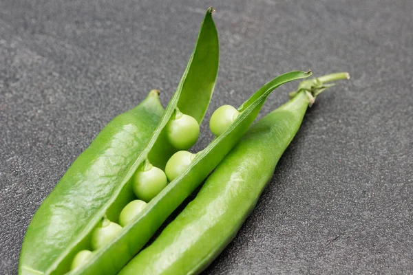 Opened green pea pod. Pea pods on table. Black background. Top view