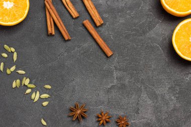 Üç yıldızlı anason kakule. Arka planda dilimlenmiş portakal ve tarçın çubukları var. Siyah arka plan. Düz yatıyordu