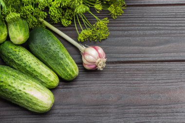 Fresh cucumbers. Dill sprigs with seeds and head of garlic. Wooden background. Top view. Copy space