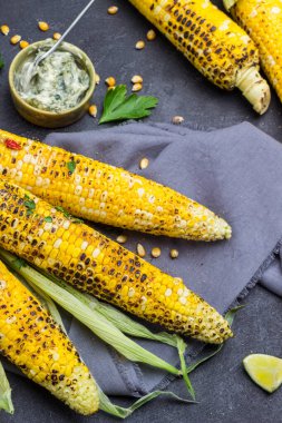 Gri peçetede ızgara mısır. Kasede sos. Siyah arka plan. Üst görünüm