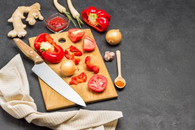 Domates, kırmızı biber ve bıçak. Bej peçete. Zencefil kökü, soğan ve kaşık masada. Uzayı kopyala Siyah arka plan. Üst görünüm