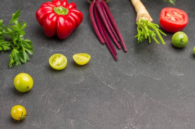 Küçük yeşil domates, biber ve maydanoz filizi, masada yarım kırmızı domates. Uzayı kopyala Siyah arka plan. Üst görünüm