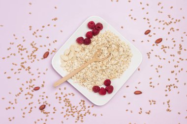 Buğday gevreği, kabak çekirdeği ve ahududu tabakta. Masada buğday taneleri. Düz yatıyordu. Pembe arkaplan