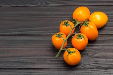 Yeşil dalda sarı domatesler. Uzayı kopyala Karanlık ahşap arka plan. Üst görünüm