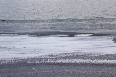 Kışın bir nehir. Kıyıya yakın buz ve kar ve arka planda su.