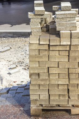 Bir palette gri granit kiremitler ve beton tuğlalar. Kaldırımları onarmak için yapı malzemeleri.