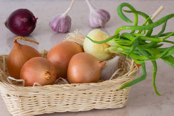 Groene uien, knoflook en rode uien in rieten mand — Stockfoto