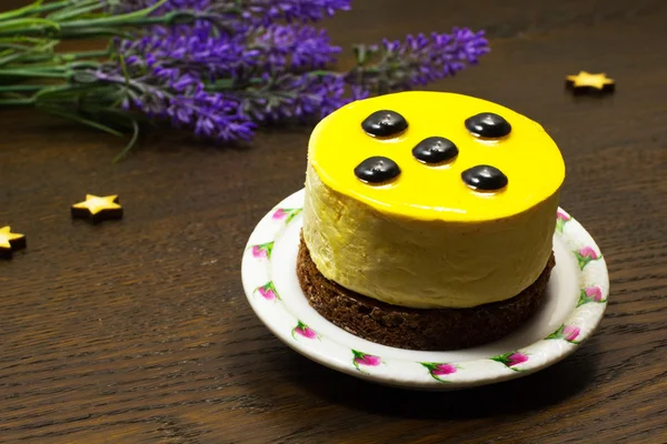 Gâteau sur une soucoupe ; fleurs et étoiles sur un fond sombre — Photo