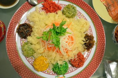 Özel yemek sırasında Çin yeni yılı Yusheng veya Yee Sang adı verilen