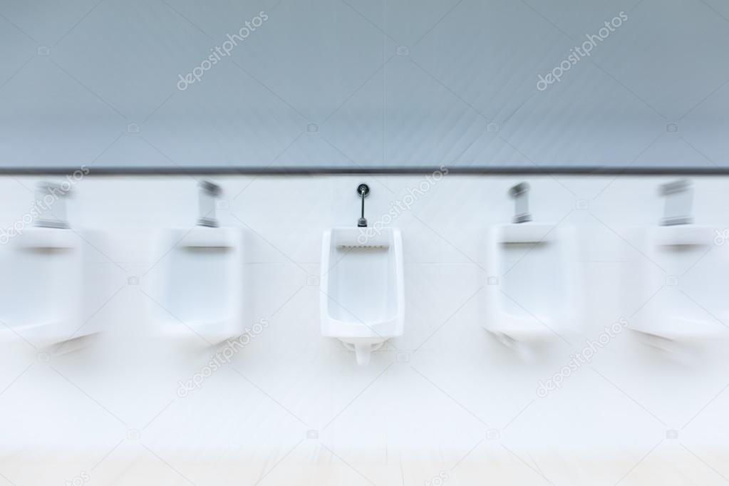 Line of white urinals in public bathroom with zoom blured Stock Photo