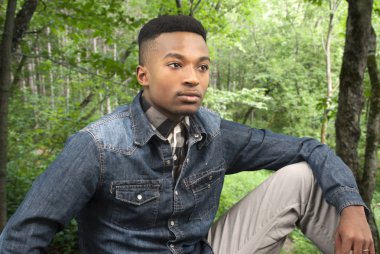 genç adam oturmuş, yeşil ormanda yağmur sonrası dinlenme