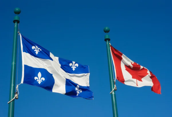 Bandeiras do Quebec e do Canadá agitam-se no vento juntas no céu azul — Fotografia de Stock
