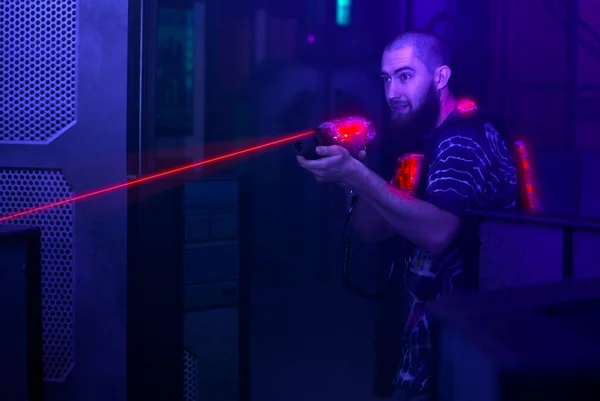 Lazer tag oyuncusu siyah ışıkta hafif silah bilimkurgu yeleği ateşliyor 