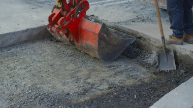 Adam, sokak inşaatındaki mekanik kazıcının yanında kürekle çalışıyormuş.