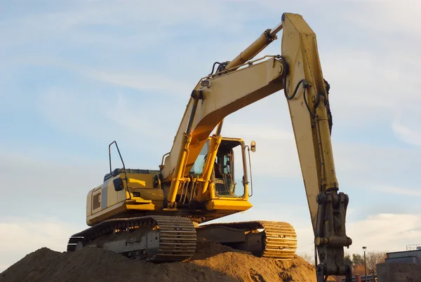 Yellow excavator on sandpile in construction site — Stock Photo, Image