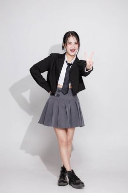 Enerjik bir Asyalı kızın yumruklarıyla tezahürat yapan vücut portresi. Zafer, başarı ve başarı kavramı. Neşeli genç bir kadın sevinçten çığlık atıyor. Sürpriz, mutluluk, iyi haberler..