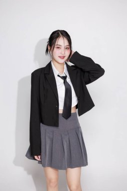 K-Pop idolü gibi titreşen Asyalı bir kadın, siyah ceket ve kravat takıyor. Kore moda trendleri, müzik videoları veya eğlence içeriği konsepti.