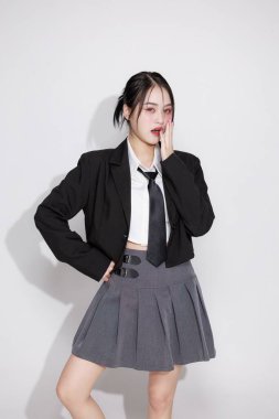 K-Pop idolü gibi titreşen Asyalı bir kadın, siyah ceket ve kravat takıyor. Kore moda trendleri, müzik videoları veya eğlence içeriği konsepti.
