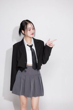 K-Pop idolü gibi titreşen Asyalı bir kadın, siyah ceket ve kravat takıyor. Kore moda trendleri, müzik videoları veya eğlence içeriği konsepti.