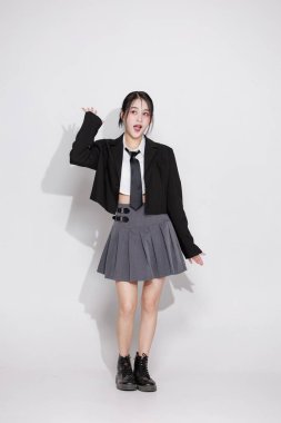 Enerjik bir Asyalı kızın yumruklarıyla tezahürat yapan vücut portresi. Zafer, başarı ve başarı kavramı. Neşeli genç bir kadın sevinçten çığlık atıyor. Sürpriz, mutluluk, iyi haberler..