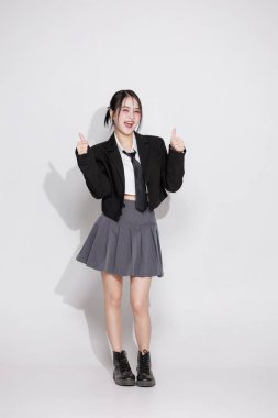 Enerjik bir Asyalı kızın yumruklarıyla tezahürat yapan vücut portresi. Zafer, başarı ve başarı kavramı. Neşeli genç bir kadın sevinçten çığlık atıyor. Sürpriz, mutluluk, iyi haberler..