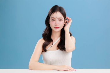 Güzel, genç Asyalı bir kadın güzel gözler doğal makyajlı saçlar izole edilmiş mavi arka planda temiz bir cilt. Tatlı kız portresi, yüz bakımı, vücut bakımı, güzellik ve güzellik merkezi..