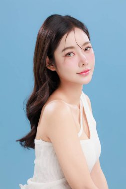 Güzel, genç Asyalı bir kadın güzel gözler doğal makyajlı saçlar izole edilmiş mavi arka planda temiz bir cilt. Tatlı kız portresi, yüz bakımı, vücut bakımı, güzellik ve güzellik merkezi..