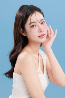 Güzel, genç Asyalı bir kadın güzel gözler doğal makyajlı saçlar izole edilmiş mavi arka planda temiz bir cilt. Tatlı kız portresi, yüz bakımı, vücut bakımı, güzellik ve güzellik merkezi..