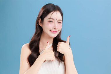 Güzel, genç Asyalı bir kadın güzel gözler doğal makyajlı saçlar izole edilmiş mavi arka planda temiz bir cilt. Tatlı kız portresi, yüz bakımı, vücut bakımı, güzellik ve güzellik merkezi..