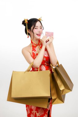 Mutlu Asyalı kadın Çin Yeni Yıl alışveriş çılgınlığına hazır. Elinde altın çantalar ve kredi kartı var. Büyük satışlar, indirimler ve tatil promosyonlarını temsil ediyor..