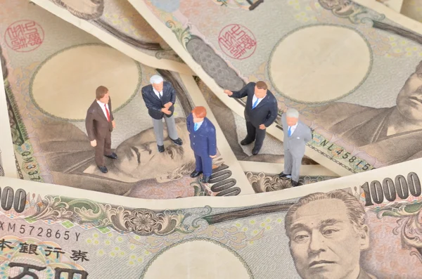 miniature businessman standing on japan dollar.