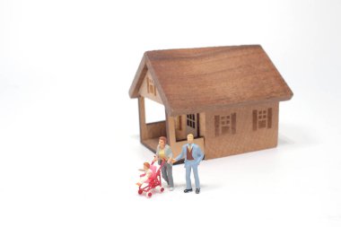 Minyatür heykelciklerden oluşan genç bir aile bir evin önünde.