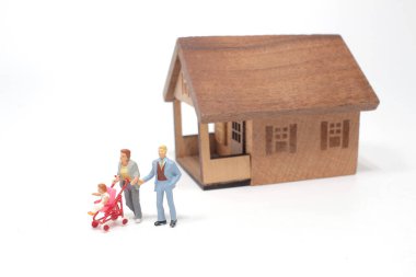 Minyatür heykelciklerden oluşan genç bir aile bir evin önünde.