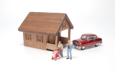 Minyatür heykelciklerden oluşan genç bir aile bir evin önünde.