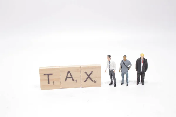 figure businessman standing beside colorful wooden TAX word