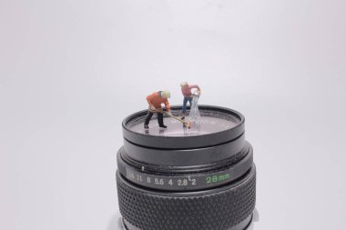 Küçük insanlar sanat eseri, bir figür insan kamera lensini temizliyor.