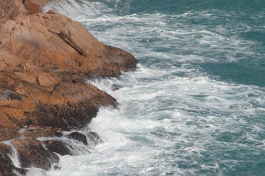 Büyük dalgalar ve fırtınalı denizde karanlık kayalar Po Toi Adaları