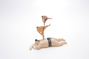 Beyaz panodaki mini Sumo figürleri yığını.