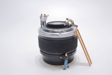 Minyatür insanlar kamerayı temizliyor.