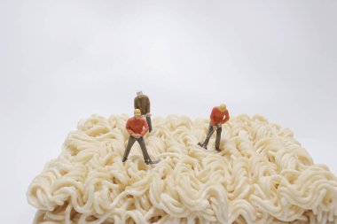 mini worker holding a rake. He is working with noodles