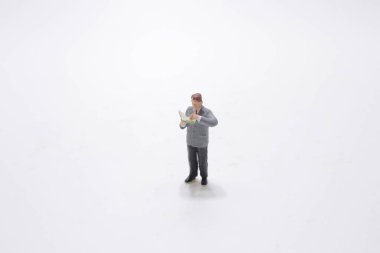 Bir kitap okurken, minyatür figür ayakta durur 